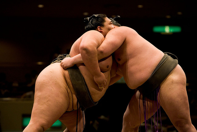 2 lutteurs de taille colossale, combattant l'un contre l'autre dans une arène